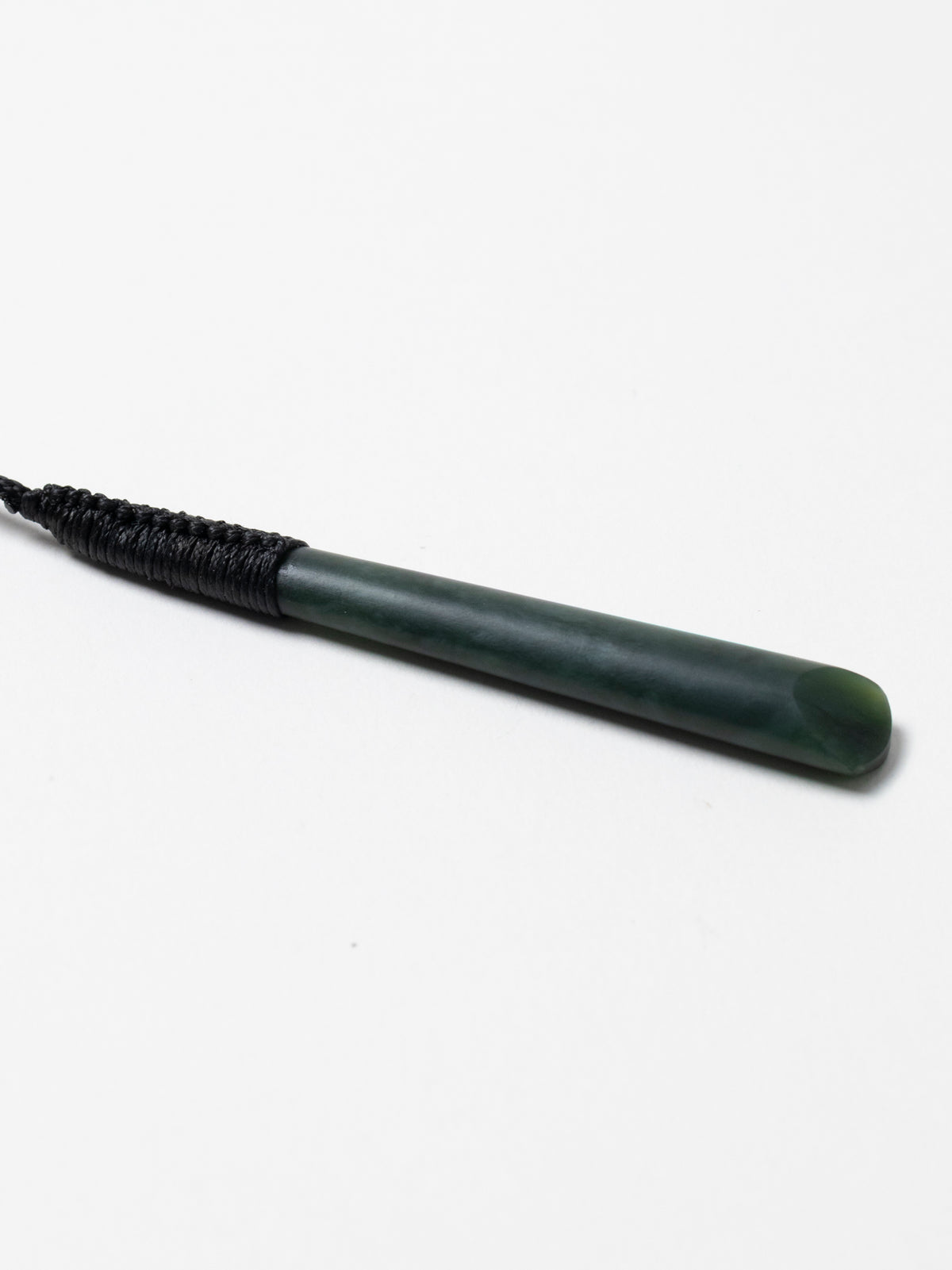 Angled close-up of the narrow Kawakawa pounamu toki pendant