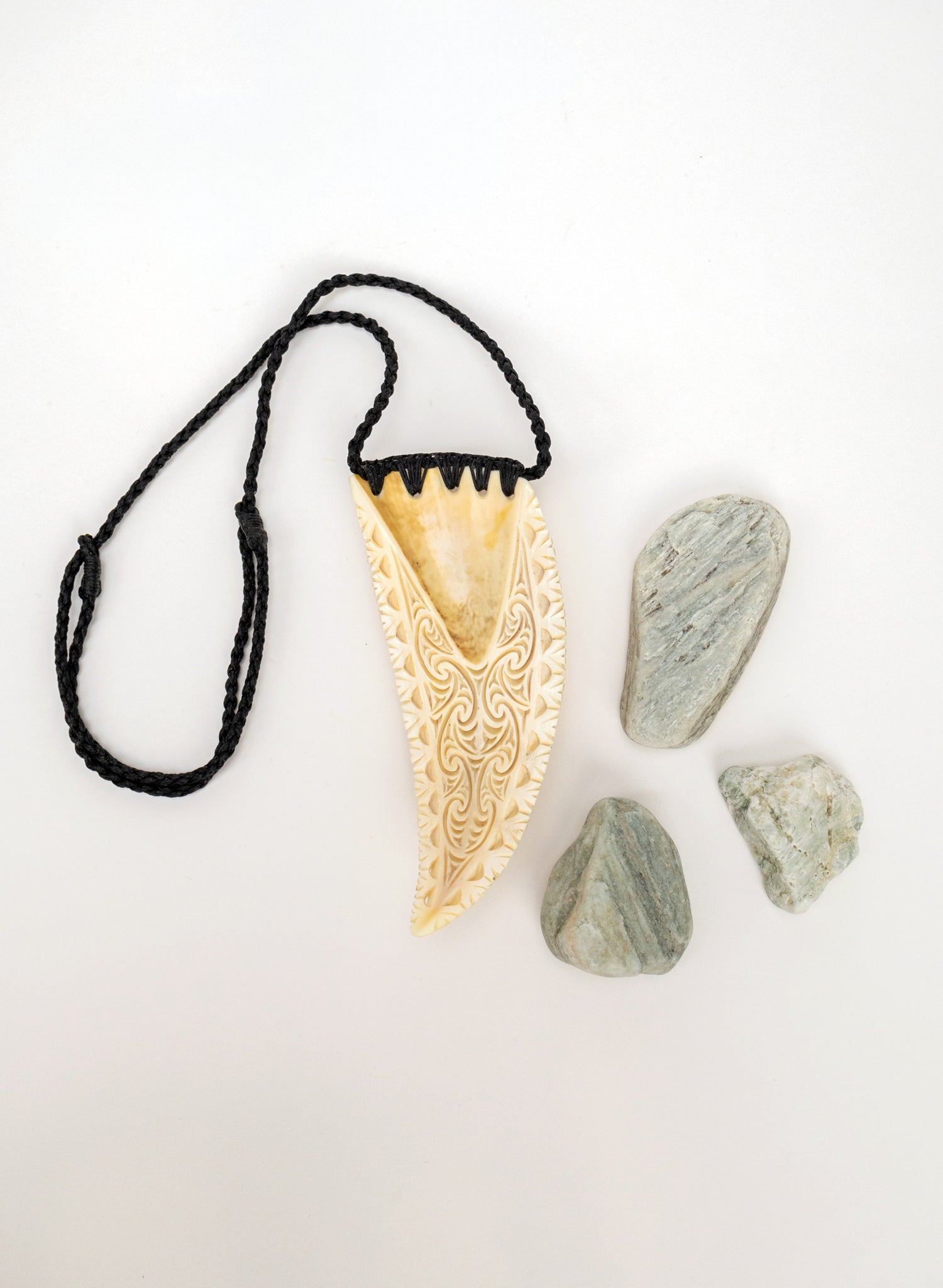 Carved Rei Puta Niho Parāoa Necklace on a stand