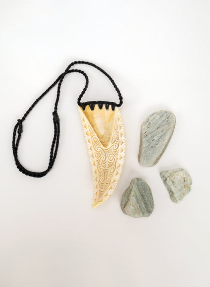 Carved Rei Puta Niho Parāoa Necklace on a stand