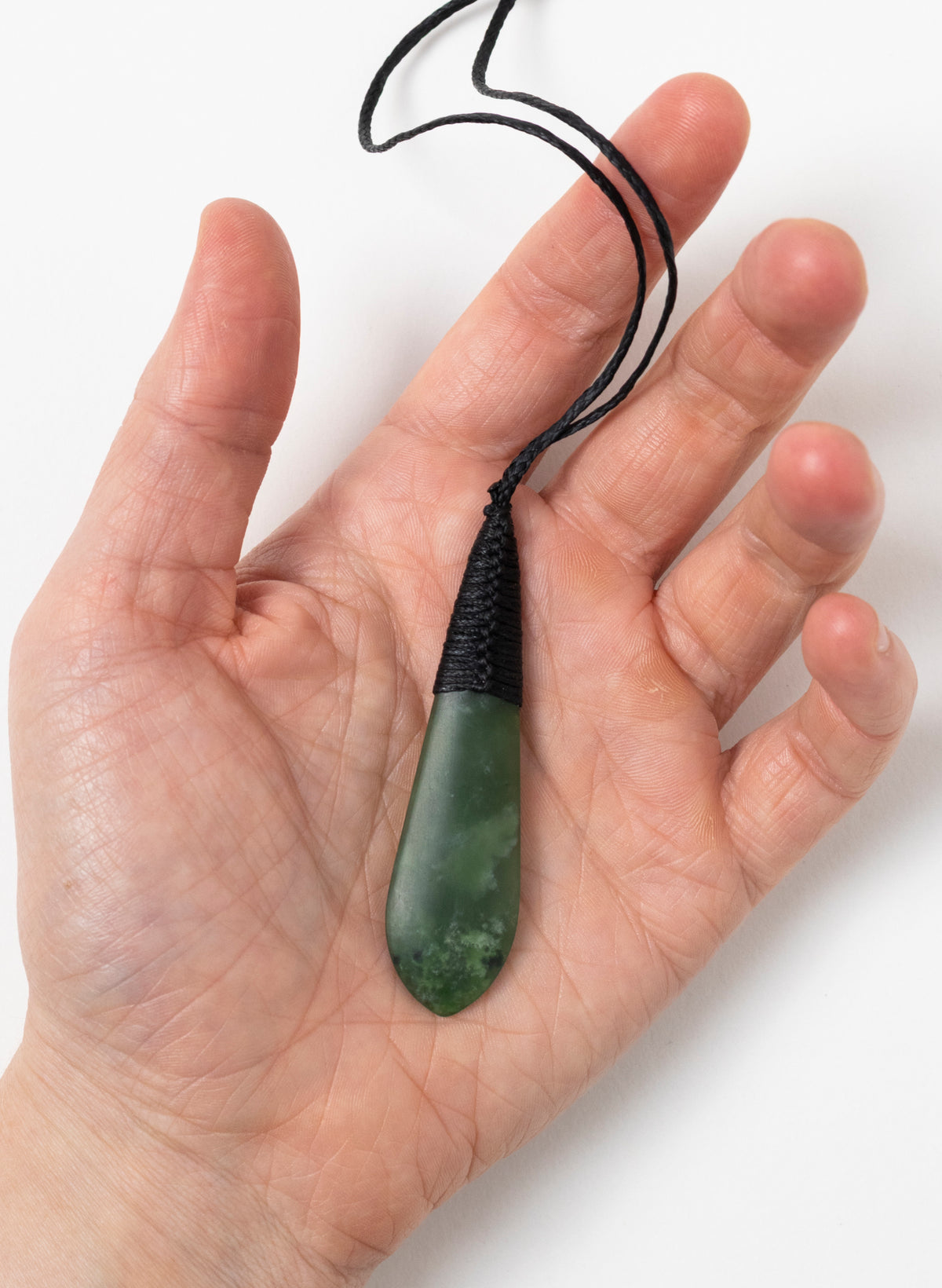 Green Kahurangi pounamu roimata pendant resting in a hand to show its size