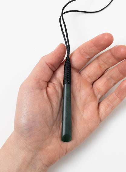 Long Kawakawa pounamu toki pendant resting in a hand to show its size