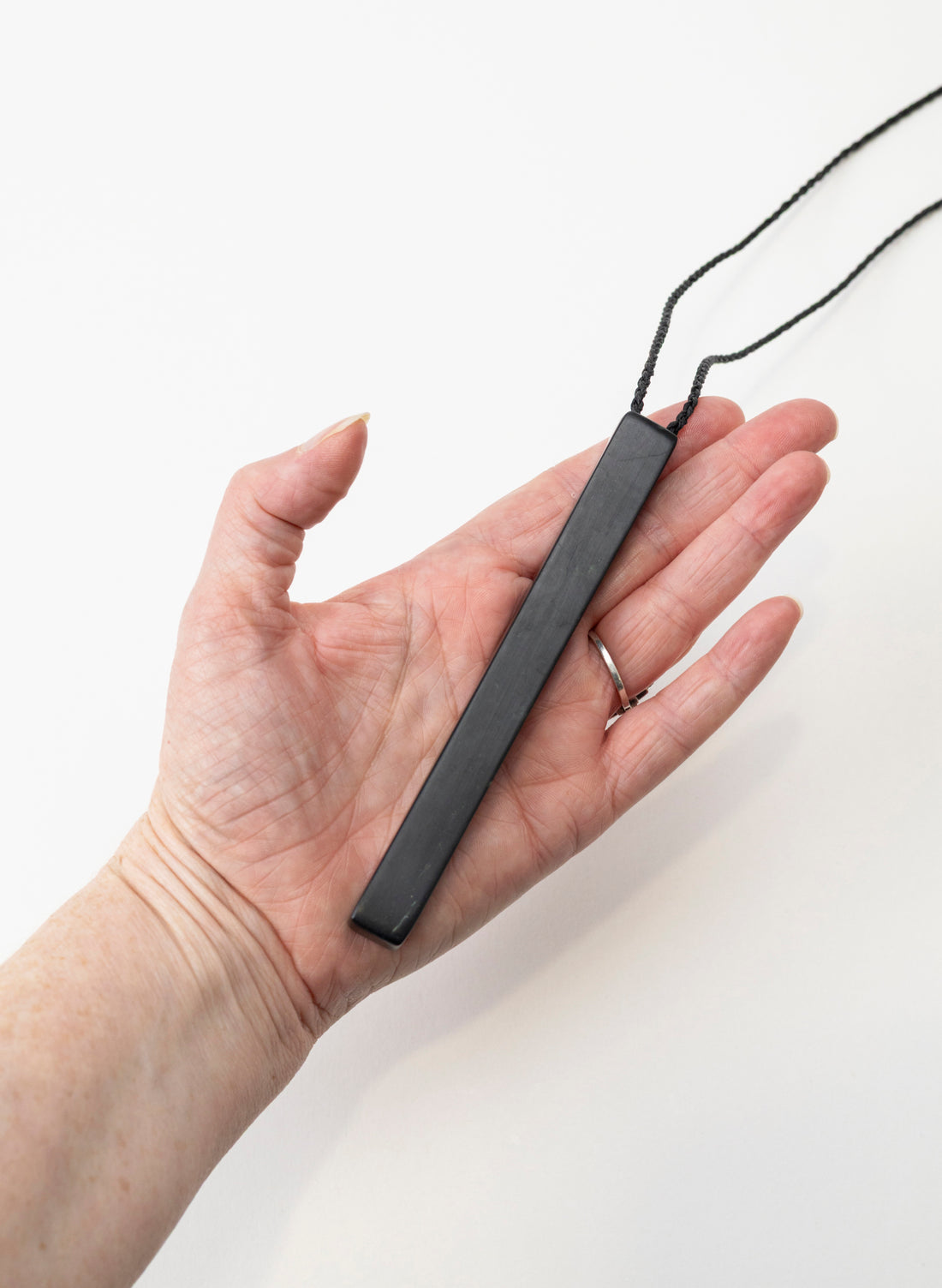Pounamu Cuisenaire Rods pendant resting in a hand to show its length