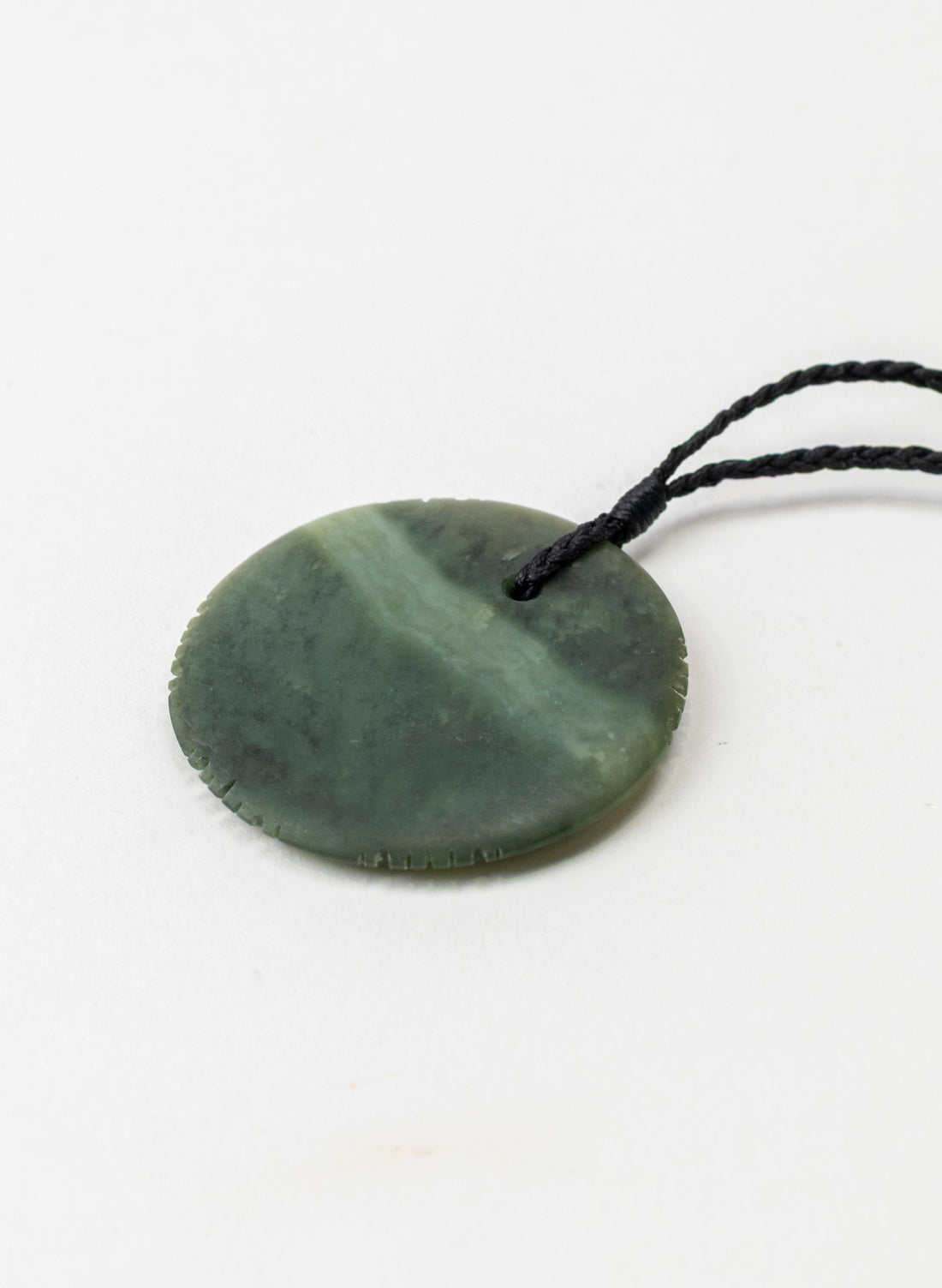 Angled close-up of the pounamu porohita pendant pale band and notched edge