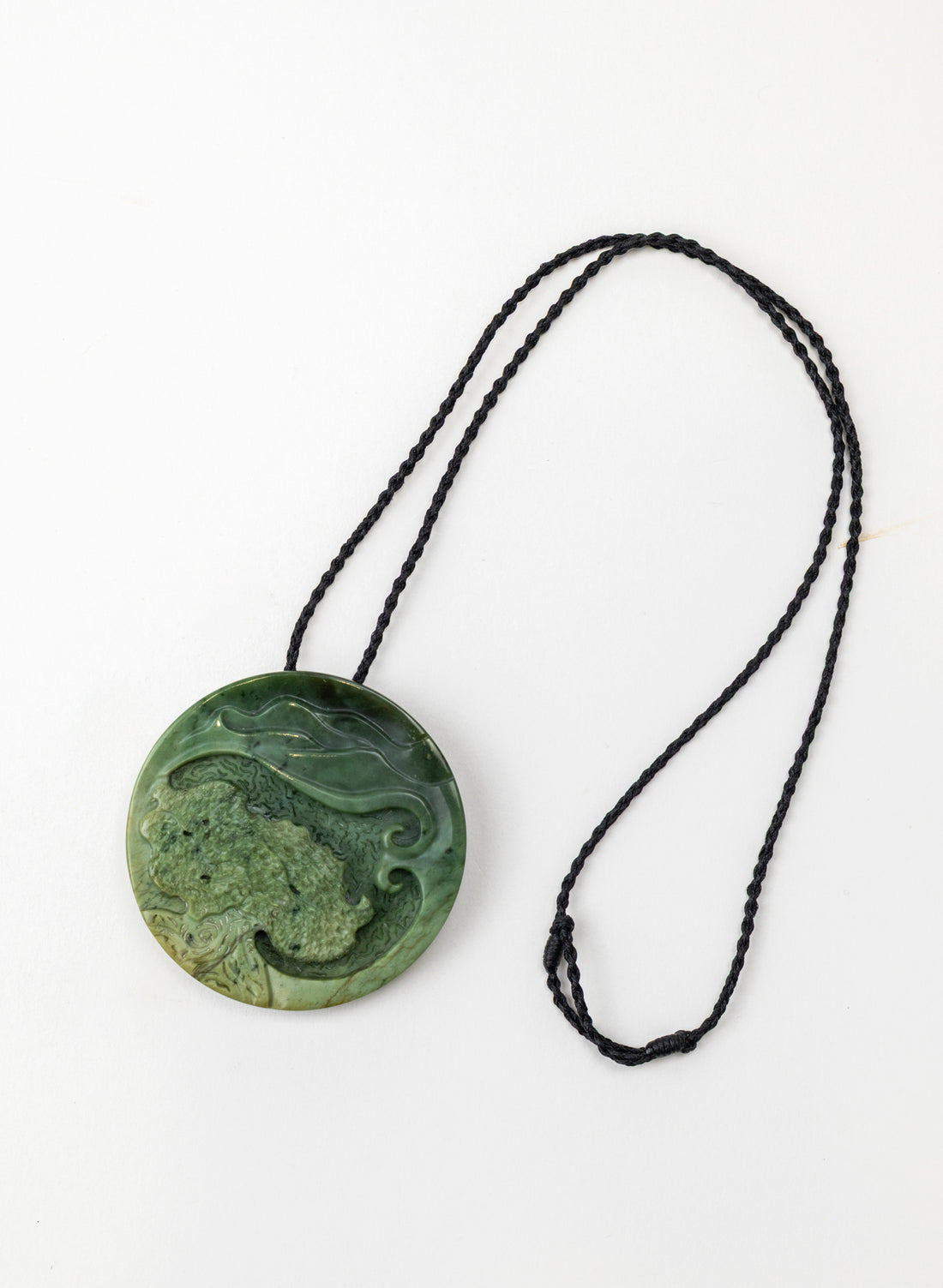 Round carved pounamu porohita with its full black cord