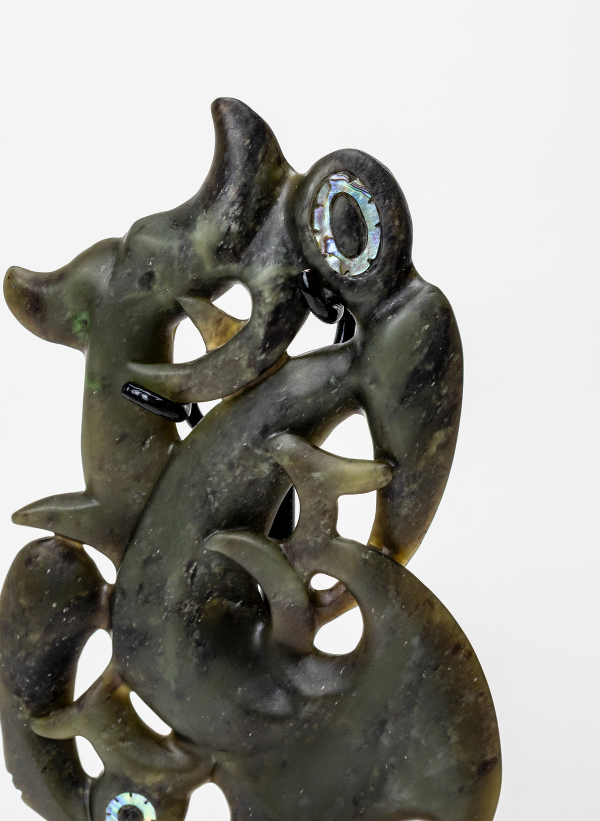 Manaia Pounamu on a Stand, close-up of the carved head, eye and openwork curves