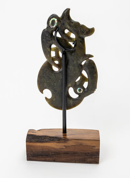 Manaia Pounamu on a Stand, rear view showing the black support rod and wooden base