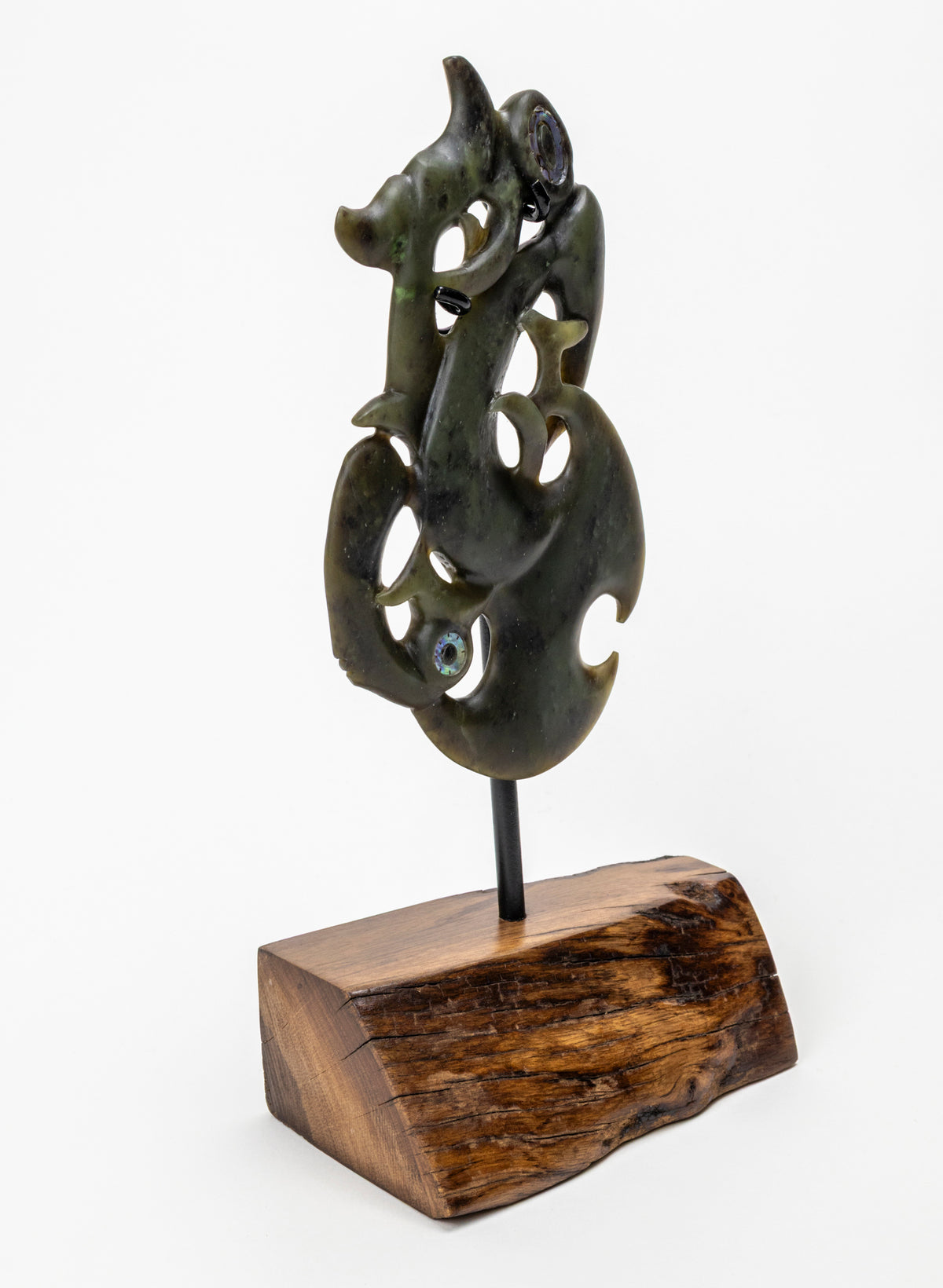 Manaia Pounamu on a Stand, angled side view of the carving on its wooden base
