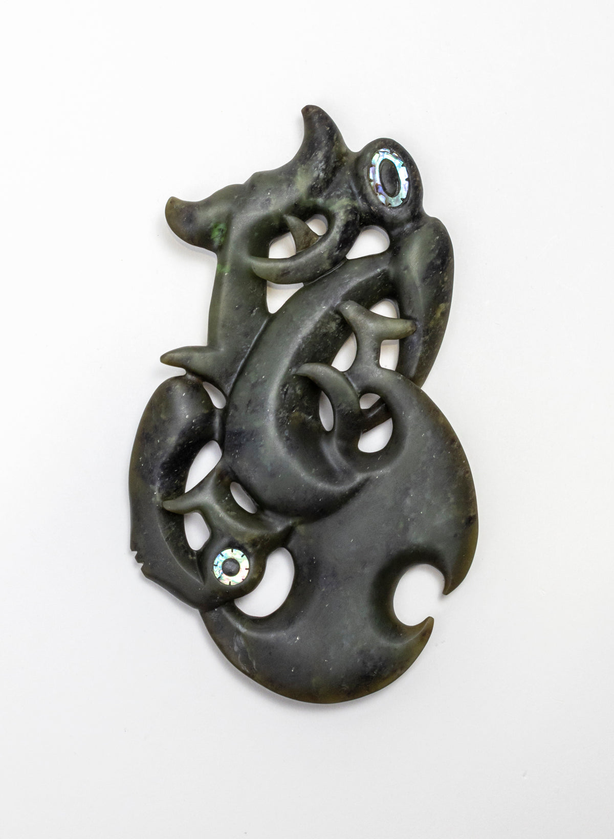 Manaia Pounamu on a Stand, dark green carving laid flat on a white background