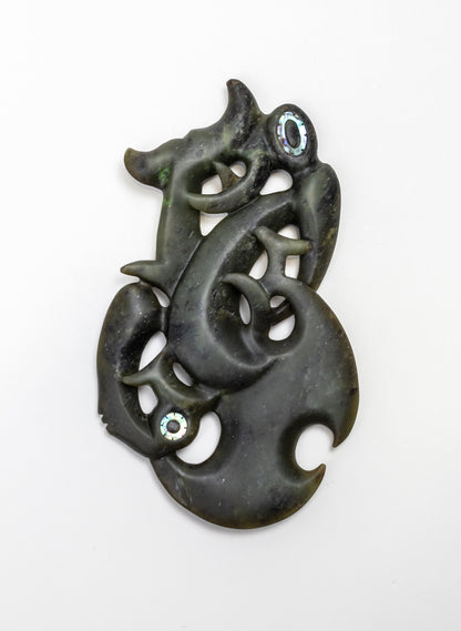Manaia Pounamu on a Stand, dark green carving laid flat on a white background